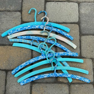 Puede incluir: Un conjunto de perchas de pl&aacute;stico azul y blanco con patrones. Las perchas son de diferentes tama&ntilde;os y tienen una variedad de patrones.