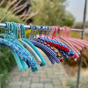 Puede incluir: Una colecci&oacute;n de perchas con patrones coloridos con dise&ntilde;os azules, blancos, rojos y rosas. Las perchas est&aacute;n hechas de un material suave y flexible y son perfectas para colgar ropa.