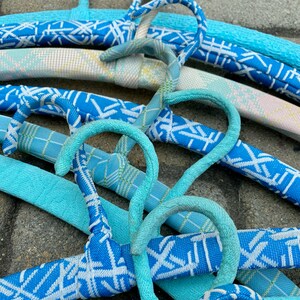 Puede incluir: Primer plano de un conjunto de perchas con estampado azul y blanco. Las perchas son de pl&aacute;stico y tienen un acabado liso y brillante. Las perchas est&aacute;n dispuestas en forma de cruz, creando una exhibici&oacute;n visualmente atractiva.