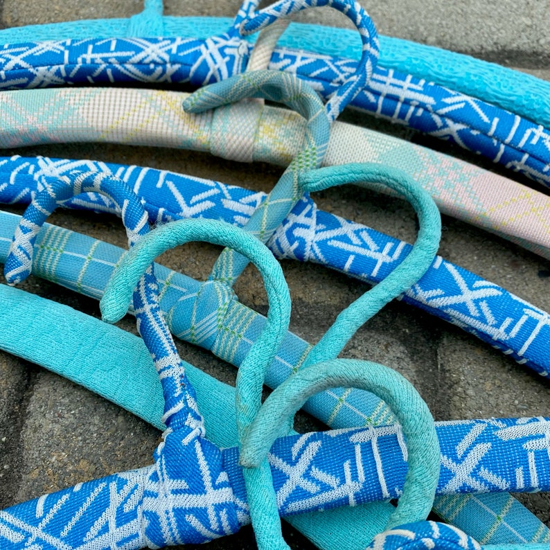 Puede incluir: Primer plano de un conjunto de perchas con estampado azul y blanco. Las perchas son de pl&aacute;stico y tienen un acabado liso y brillante. Las perchas est&aacute;n dispuestas en forma de cruz, creando una exhibici&oacute;n visualmente atractiva.