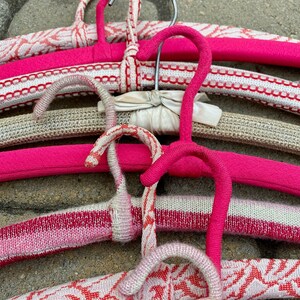 Puede incluir: Un conjunto de perchas coloridas y estampadas con detalles en rosa, blanco y gris. Las perchas est&aacute;n hechas de un material suave y flexible y est&aacute;n dise&ntilde;adas para colgar ropa.