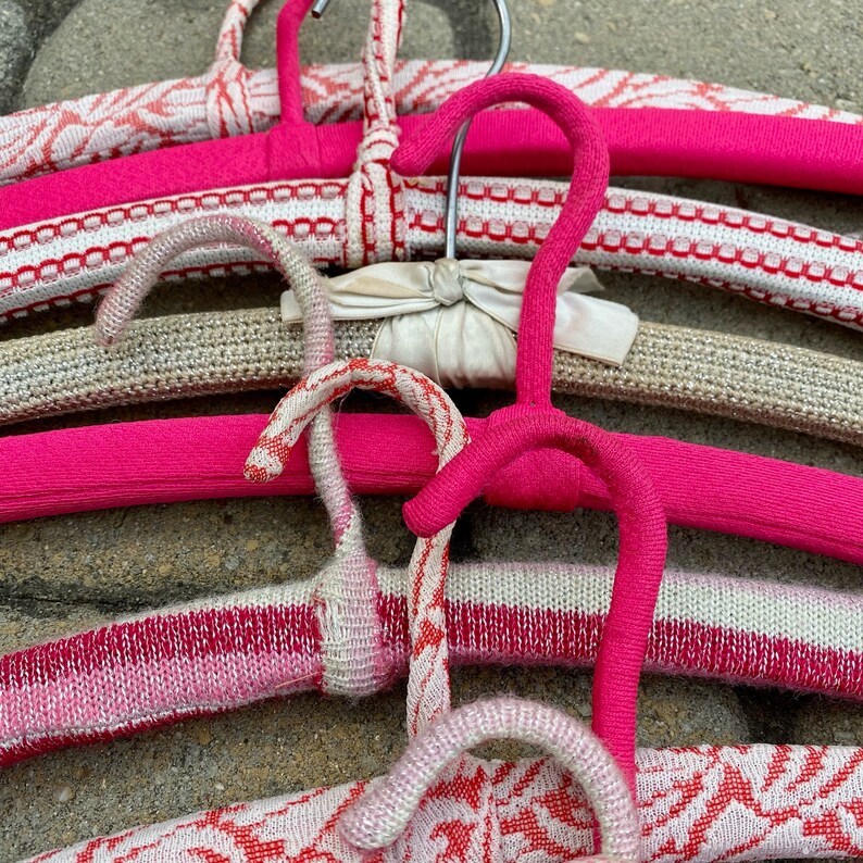 Puede incluir: Un conjunto de perchas coloridas y estampadas con detalles en rosa, blanco y gris. Las perchas est&aacute;n hechas de un material suave y flexible y est&aacute;n dise&ntilde;adas para colgar ropa.