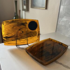 May include: Three amber-colored trays with black marbling. The top tray has a circular indentation.