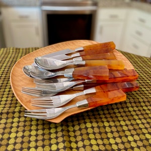 May include: A set of amber-colored handled silverware on a wooden tray. The set includes forks, spoons, and a butter knife.