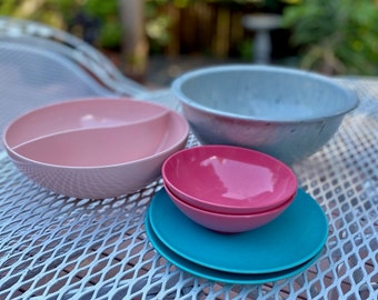 May include: A set of four bowls in various colors and sizes. The bowls are made of plastic and are perfect for serving salads, snacks, or desserts. The bowls are arranged on a white metal table.