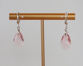 May include: A pair of silver dangle earrings with pink teardrop-shaped crystals.