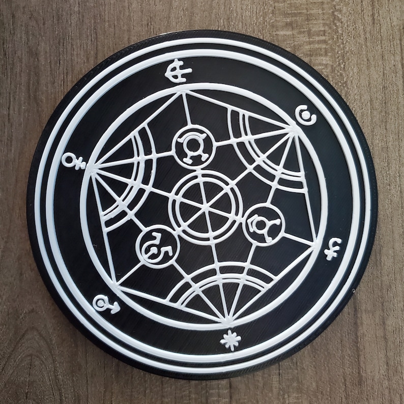 Puede incluir: Posavasos circular negro y blanco con un dise&ntilde;o geom&eacute;trico que presenta una estrella central y varios s&iacute;mbolos. El dise&ntilde;o recuerda a un s&iacute;mbolo m&aacute;gico o m&iacute;stico.