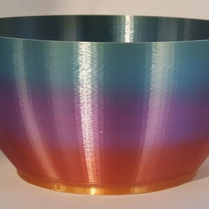 May include: A large, iridescent bowl with a gradient of teal, purple, and orange colors. The bowl has a gold rim.