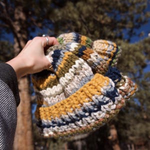 May include: A colorful knitted hat with stripes of yellow, blue, white, and green.