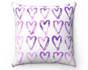 Pode incluir: Travesseiro quadrado branco com um padrão de corações de aquarela roxo.