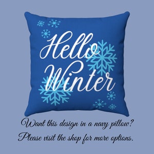 Pode incluir: Uma almofada quadrada azul marinho com as palavras "Hello Winter" em branco, acompanhada por desenhos de flocos de neve azul claro. Um item decorativo para a decora&ccedil;&atilde;o de inverno.