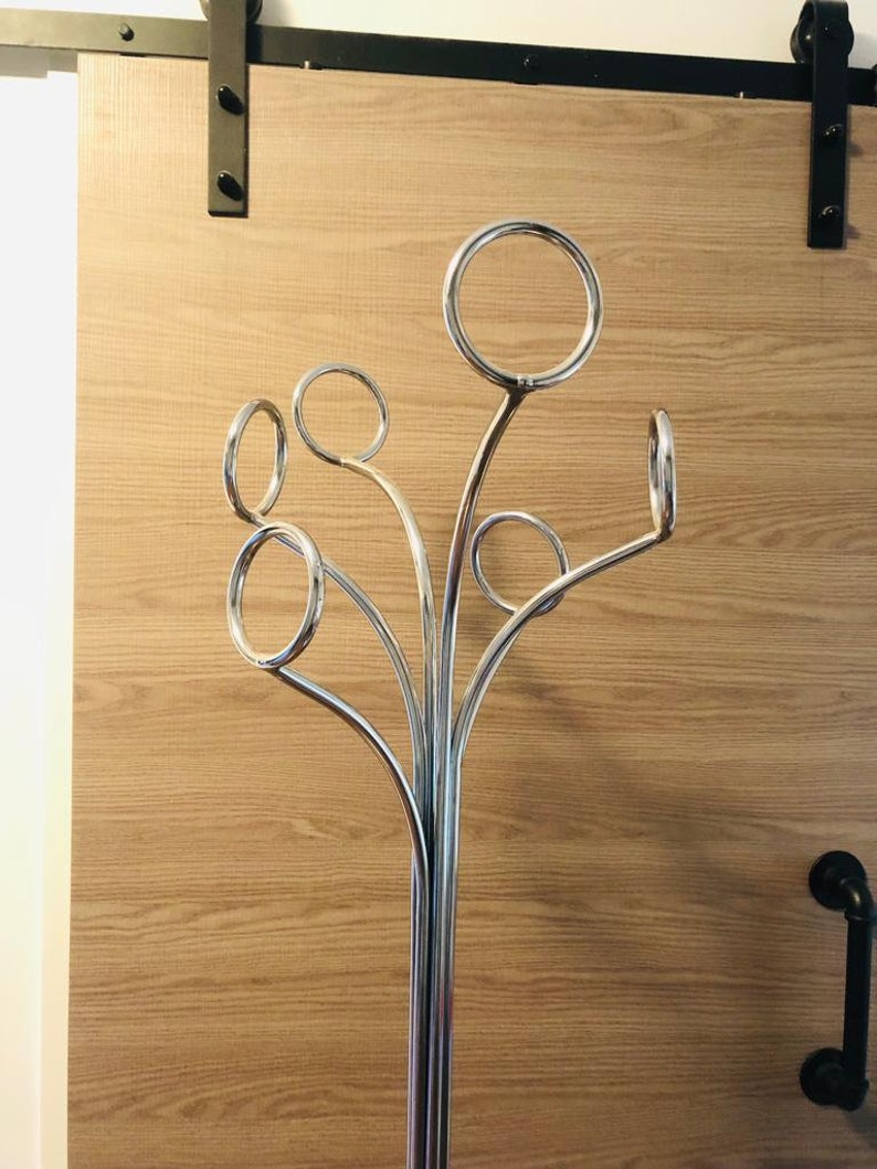 Peut inclure: Un porte-manteau en m&eacute;tal chrom&eacute; avec cinq crochets incurv&eacute;s. Le porte-manteau a une base haute et fine et un design moderne.