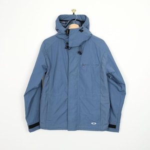 May include: A blue hooded jacket with a full front zipper, a small chest pocket, and black accents on the cuffs. The jacket has a drawstring hood and a small logo near the bottom hem. The jacket is hanging on a wooden hanger.