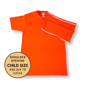 Op de afbeelding: Oranje T-shirt met witte afwerking op de schouders. Het shirt is ontworpen voor kinderen van 3/4 tot 12/13 jaar. De tekst "Shoulder Opening Child Size Age 3/4 to 12/13" is gedrukt op een gele cirkel.