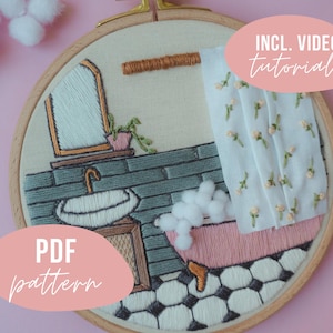 Può includere: Un telaio da ricamo raffigurante una scena di bagno con una vasca rosa con piedini riempita di bolle di pompon bianchi, un lavandino bianco, uno specchio e una tenda da doccia floreale. Il testo INCL. VIDEO TUTORIALS e PDF pattern è sovrapposto.