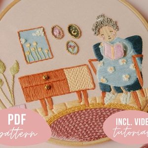 Può includere: Arte di ricamo in cerchio che presenta una donna che legge un libro su una sedia, un tavolino con cassetti e una pianta in vaso. Lo sfondo è rosa chiaro con un motivo floreale. Il testo "PDF pattern" e "INCL. VIDEO tutorials" è incluso nell'immagine.