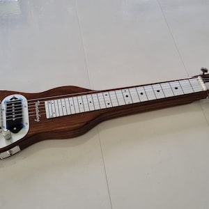 Op de afbeelding: Een bruine houten stalen gitaar met een zilveren metalen toets en verchroomde stemknoppen. De gitaar heeft één pickup en twee knoppen.