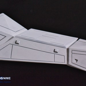 May include: A white model of a spaceship with detailed panel lines and a textured surface. The model is made of plastic and is ready for painting.