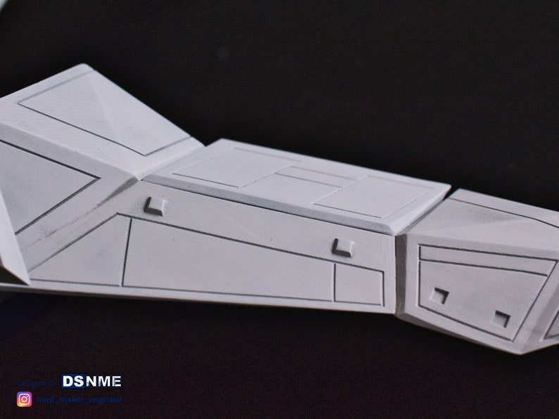 May include: A white model of a spaceship with detailed panel lines and a textured surface. The model is made of plastic and is ready for painting.
