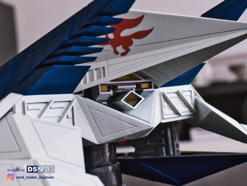 May include: A white and blue model airplane with a red and white fox logo on the wing. The model is detailed with a cockpit and a variety of panels and hatches. Designed by DSNNME.
