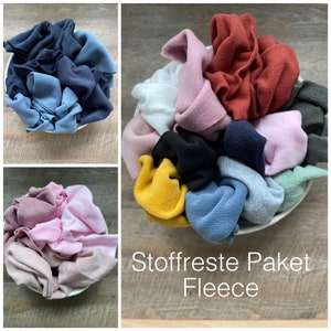 Könnte beinhalten: Eine Schüssel gefüllt mit verschiedenen Stoffresten aus Fleece in verschiedenen Farben, darunter rosa, blau, gelb, grün und rot. Der Text "Stoffreste Paket Fleece" ist unter der Schüssel sichtbar.