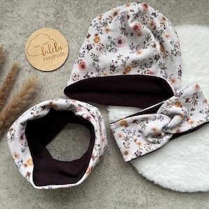 Könnte beinhalten: Ein Set aus drei Winteraccessoires im Blumenmuster. Das Set beinhaltet eine Mütze, ein Stirnband und einen Halsschmuck. Alle drei Artikel sind mit dunkelbraunem Fleece gefüttert.