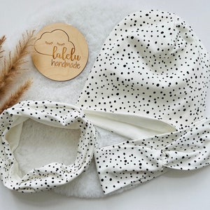 Könnte beinhalten: Ein weißes Stirnband mit schwarzen Punkten, eine weiße Mütze mit schwarzen Punkten und ein Holzschild mit der Aufschrift "lalelu handmade".