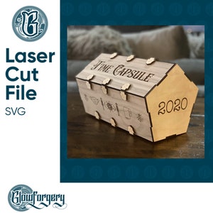 May include: A wooden time capsule box with the text "Time Capsule" and "2020" engraved on it. The box has a hinged lid and is decorated with various symbols, including a face mask, a knife, a virus, a toilet paper roll, and a bee.