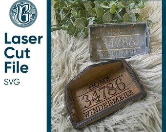 May include: Two wooden trays with engraved text. The top tray is gray with white text that reads "HOME 34786 WINDERMERE". The bottom tray is brown with white text that reads "HOME 34786 WINDERMERE".