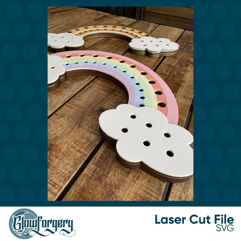 May include: Two rainbow-coloured wooden yarn holders with cloud-shaped bases. The rainbow holders have holes for yarn and are layered in shades of pink, orange, and yellow. The clouds are white and have holes for yarn.
