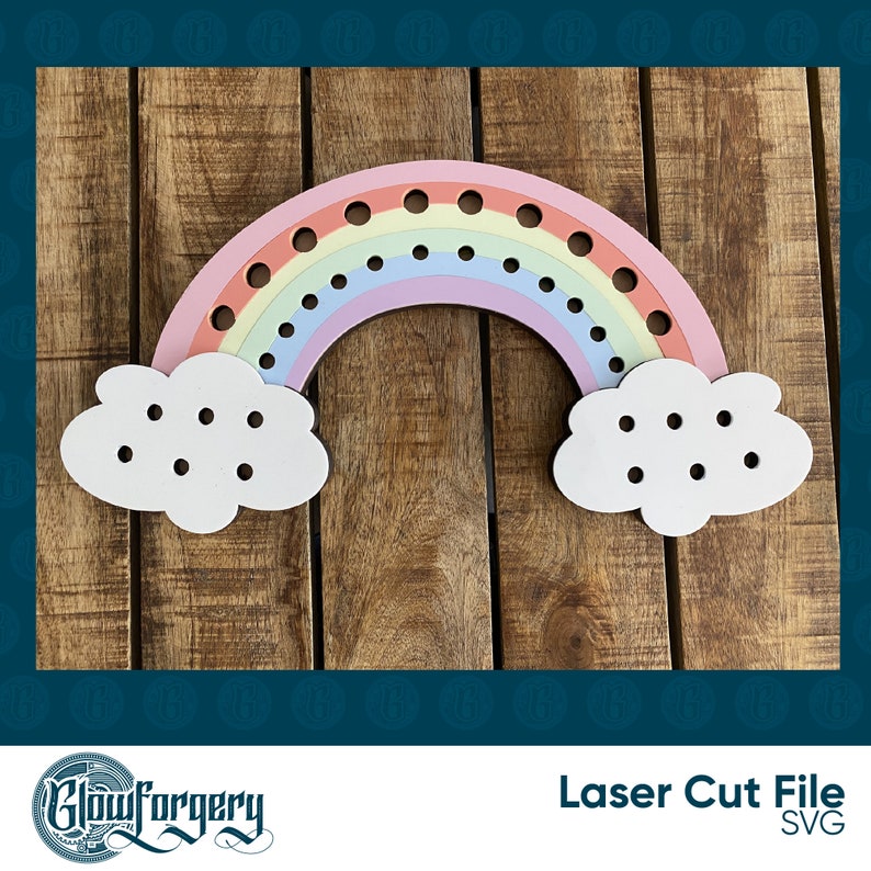 May include: A wooden rainbow cutout with clouds on either side. The rainbow has holes for threading string or yarn. The clouds also have holes for threading. The rainbow is pink, orange, yellow, green, blue, and purple. The clouds are white. The background is a wooden surface.