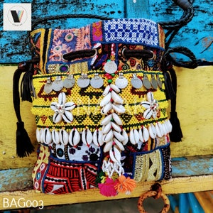 Puede incluir: Una bolsa de cordón colorida con un diseño de patchwork, con conchas, cuentas y monedas. La bolsa tiene un cordón y una correa negros.