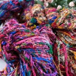 K&ouml;nnte beinhalten: Nahaufnahme eines bunten Garns aus recycelten Seidenstoffresten. Das Garn ist eine Mischung aus Rosa, Blau, Gr&uuml;n und Wei&szlig;.