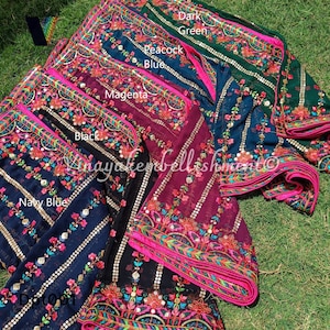Pode incluir: Uma pilha de seis sarees de chiffon coloridos com desenhos florais bordados e lantejoulas. Os sarees estão dispostos em degradê de verde escuro para azul marinho. As cores são rotuladas como "Verde escuro", "Azul pavão", "Magenta", "Preto", "Azul marinho" e "Dot001".