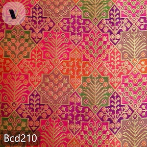 Puede incluir: Primer plano de una tela vibrante con un patr&oacute;n geom&eacute;trico repetitivo. El dise&ntilde;o presenta motivos florales y de hojas en tonos de rosa, naranja, morado y verde, acentuados con hilo met&aacute;lico dorado. El texto "Bcd210" es visible en la parte inferior.