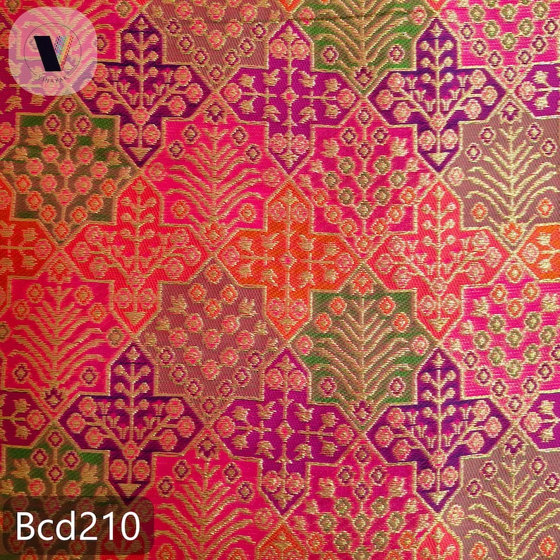 Puede incluir: Primer plano de una tela vibrante con un patr&oacute;n geom&eacute;trico repetitivo. El dise&ntilde;o presenta motivos florales y de hojas en tonos de rosa, naranja, morado y verde, acentuados con hilo met&aacute;lico dorado. El texto "Bcd210" es visible en la parte inferior.