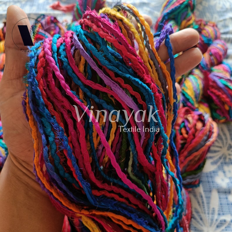 May include: A close-up of a bundle of colourful, twisted, recycled sari silk rope. The rope is made from upcycled fabric scraps and is perfect for crafting and macrame projects.