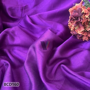 Könnte beinhalten: Ein leuchtend violetter Stoff mit weichen Falten und dezentem Glanz. Das Bild zeigt eine Nahaufnahme des Materials, mit dem Text "BCD160" in der unteren linken Ecke. Ein Blumenstrauß befindet sich in der oberen rechten Ecke.