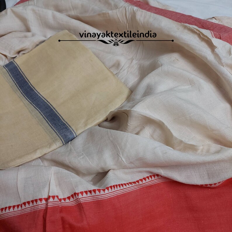 Pode incluir: Um tecido creme com uma borda vermelha e um tecido quadrado bege com uma faixa azul. O tecido &eacute; drapeado, criando dobras suaves. O texto "vinayaktextileindia" &eacute; vis&iacute;vel.