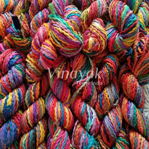 May include: A close-up of a pile of colourful, hand-spun silk ribbon yarn. The yarn is made from recycled saris and is perfect for knitting, crocheting, and macrame projects.