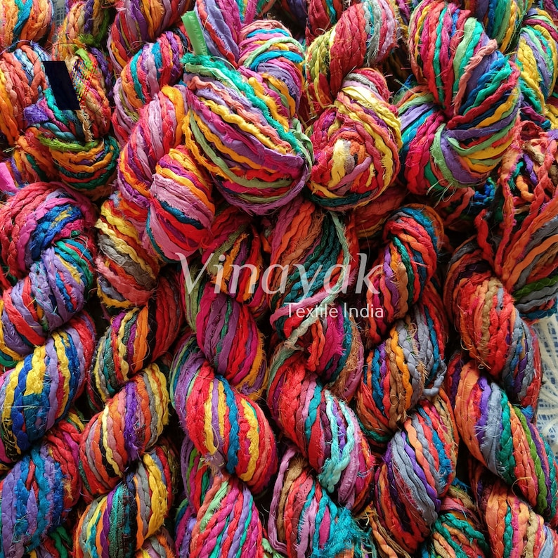 May include: A close-up of a pile of colourful, hand-spun silk ribbon yarn. The yarn is made from recycled saris and is perfect for knitting, crocheting, and macrame projects.
