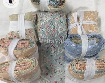 May include: Several rolls of decorative fabric trim featuring intricate floral embroidery in red, green, and white threads on sheer mesh. The collection includes various colors such as beige, light blue, and pink, all secured with white ribbon.