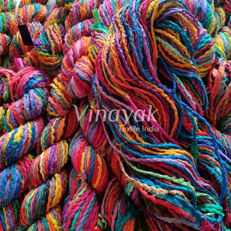 May include: A close-up of a pile of colourful, hand-spun silk yarn. The yarn is made from recycled fabric scraps and is perfect for knitting, crocheting, or weaving.