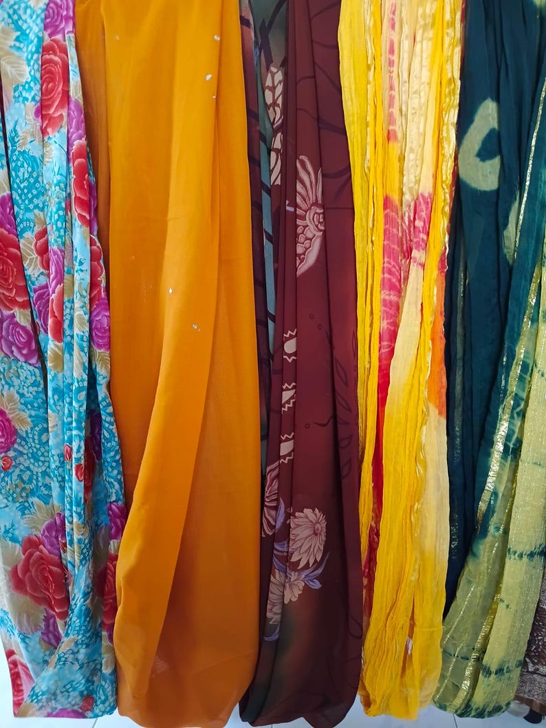 May include: A collection of five hanging fabric panels featuring diverse designs. The first is a blue floral print, the second is solid mustard yellow, the third is a dark maroon with botanical patterns, the fourth is yellow with pink tie-dye, and the fifth is a dark green with gold trim.
