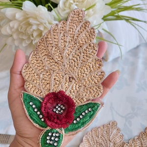 May include: A gold embroidered applique with a red flower and green leaves. The applique has a delicate, intricate design and is perfect for adding a touch of elegance to any project.