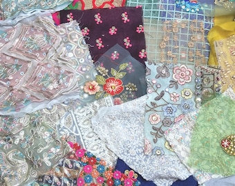 May include: A collection of assorted fabric scraps featuring intricate embroidery, sequins, and beadwork in various colors including blue, green, pink, gold, and white. The pieces display diverse floral patterns, geometric designs, and lace textures.