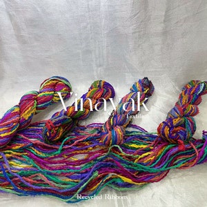 May include: A close-up of colourful recycled fabric ribbons, twisted and bundled together. The ribbons are a mix of bright colours, including red, yellow, green, blue, and purple. The text "Vinayak Textile" and "Recycled Ribbons" are visible in the image.