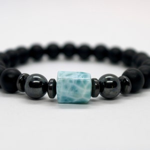 May include: A black beaded bracelet with a blue and white gemstone bead in the center.