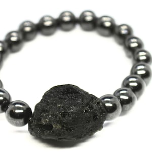 May include: A black beaded bracelet with a large, rough, black volcanic rock charm.