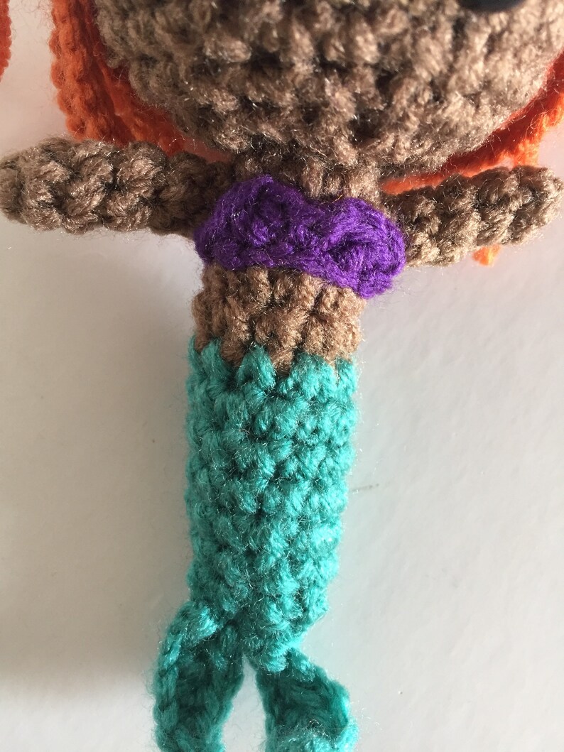 May include: Crocheted mermaid doll with brown hair, a purple top, and a teal tail.